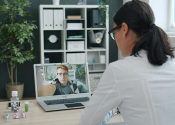Doctor consulting patient via video call on laptop.