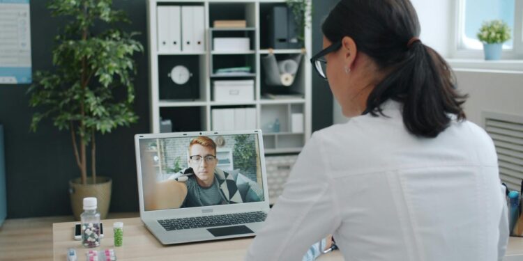 Doctor consulting patient via video call on laptop.